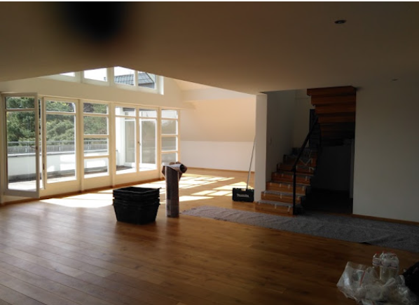 Von GSB ausgebautes Dachgeschoss in Berlin – heller Wohnraum mit Holztreppe und Glasfront